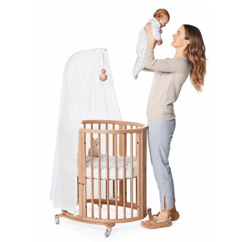 mamá cogiendo en brazos a su bebé desde la cuna sleepi de Stokke con acedor diseño ovalado